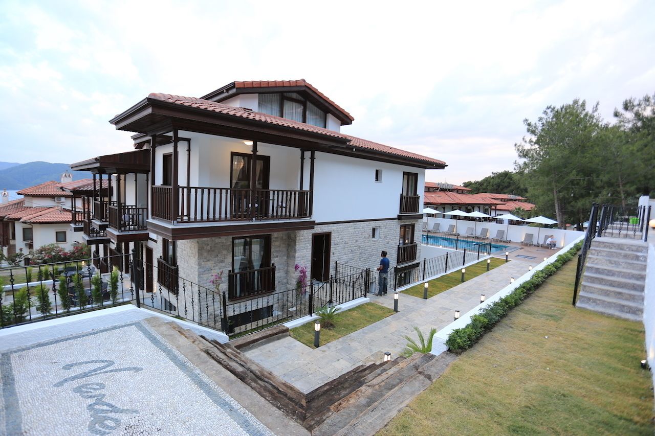 Uma casa de dois andares com varanda, piscina e gramado bem cuidado.
