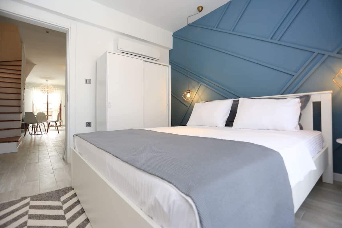 A bedroom with a bed, a wardrobe, and a desk with chairs.