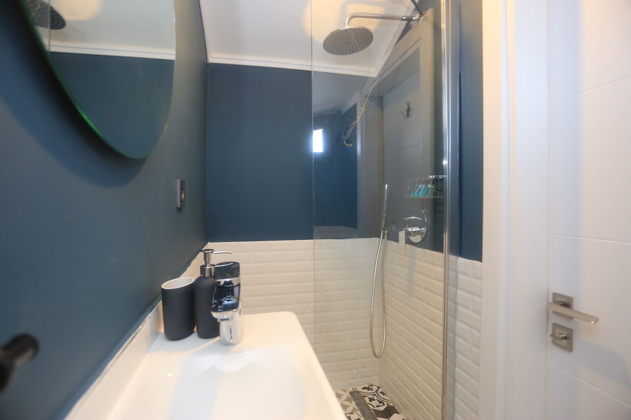 A modern bathroom with a glass shower enclosure, a white sink, and a mirror.