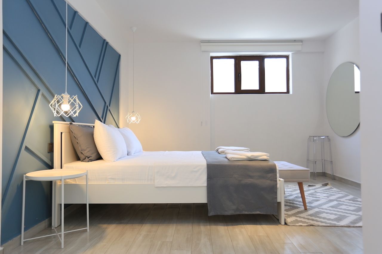 A modern bedroom with a bed, bedside table, and a window.
