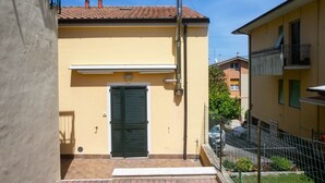A yellow building with a green door, a metal pole, and a small balcony. - S202 - Sirolo, new two-room apartment convenient to services (Sirolo)