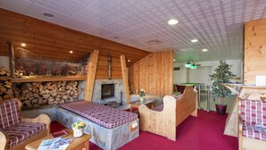 Um quarto acolhedor com móveis de madeira, lareira e uma pequena árvore de Natal.