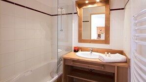 A modern bathroom with a glass-enclosed shower, a wooden vanity with a sink, and a large mirror above the vanity.