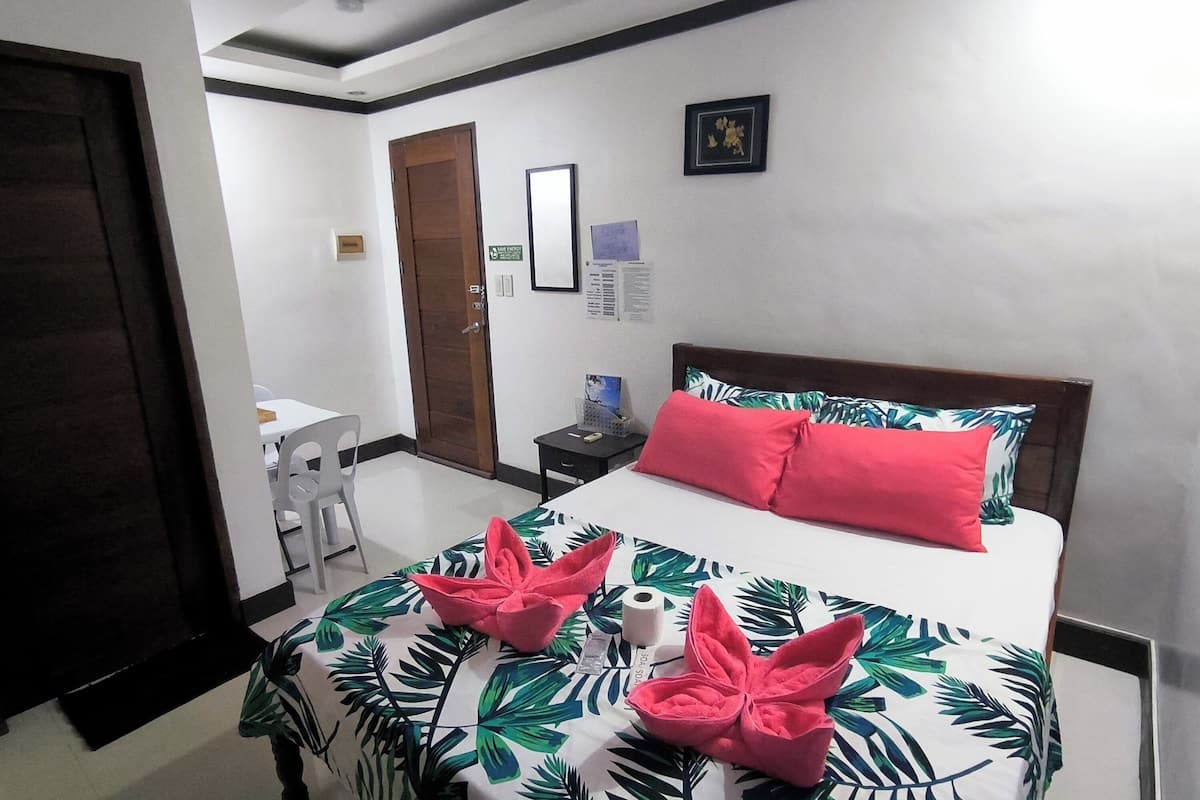 Une chambre d’hôtel avec un lit, un bureau et une chaise.