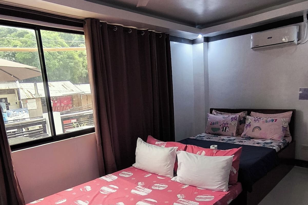 Une chambre à coucher avec un lit, un ventilateur de plafond, un climatiseur et une fenêtre avec des rideaux.