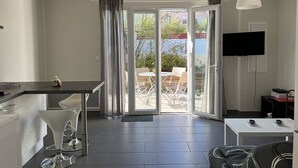 Una cocina moderna con comedor, televisor y puerta corrediza de vidrio que da a un patio exterior.