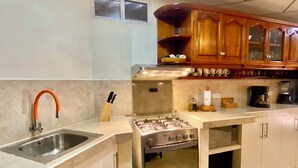 A kitchen with a stainless steel sink, a gas stove, and wooden cabinets.