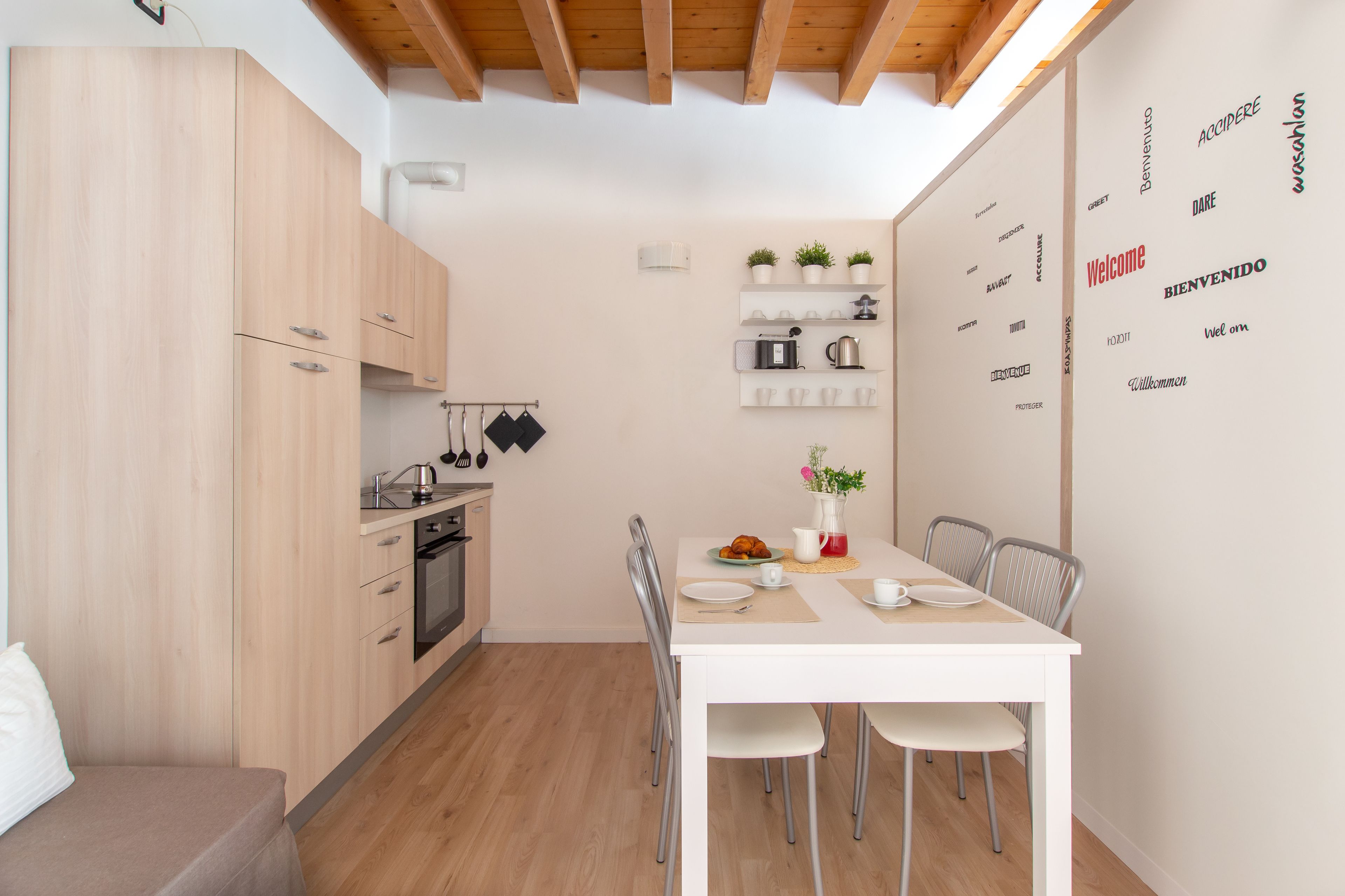 A compact kitchen with wooden cabinets, a dining table with chairs, and a breakfast setup.