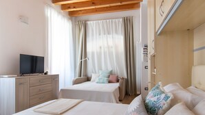 A bedroom with two beds, a desk, and a television. - Foresteria Della Corte (Como)