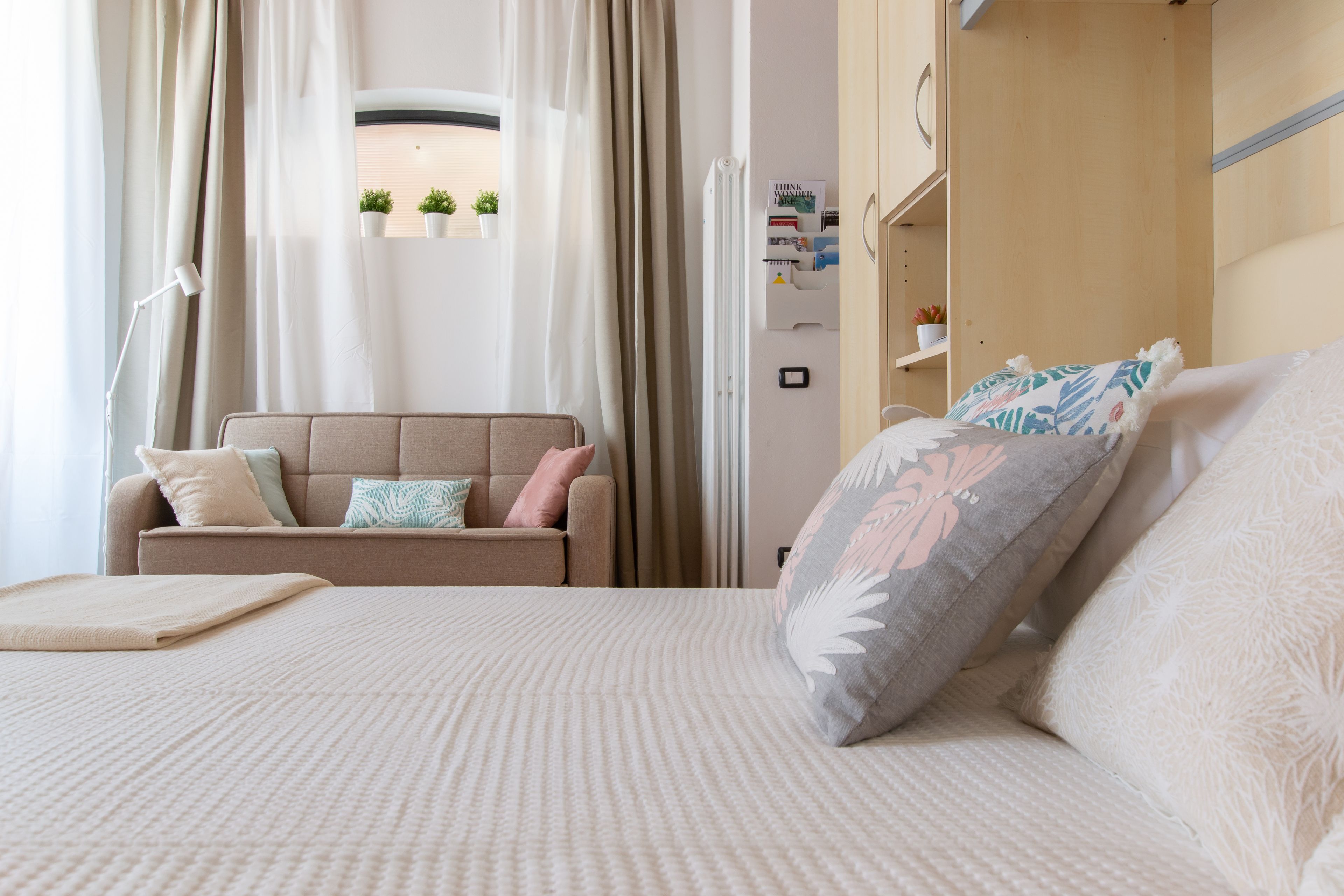 A bedroom with a bed, a sofa, and a window with curtains.