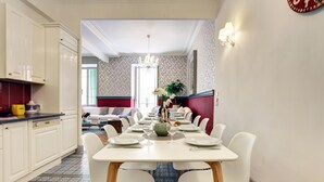 Een eetgedeelte met een lange tafel voor zes personen, witte stoelen en een kroonluchter.