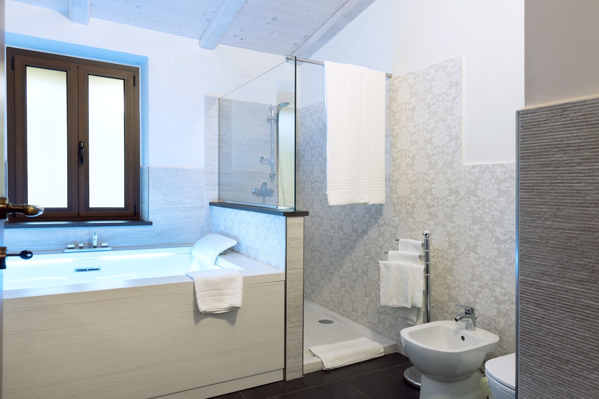 A modern bathroom with a large sink, a glass shower enclosure, a toilet, and a bidet.