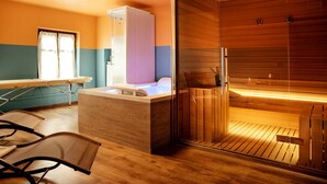 Un sauna con suelo de madera, puerta de vidrio y un banco.