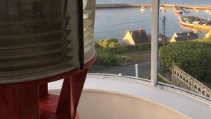 Een balkon met uitzicht op de zee en een vuurtoren.