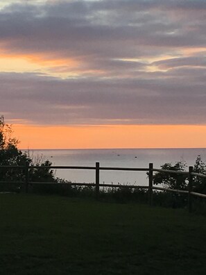 Una vista al atardecer sobre una masa de agua, con una cerca de madera al frente.