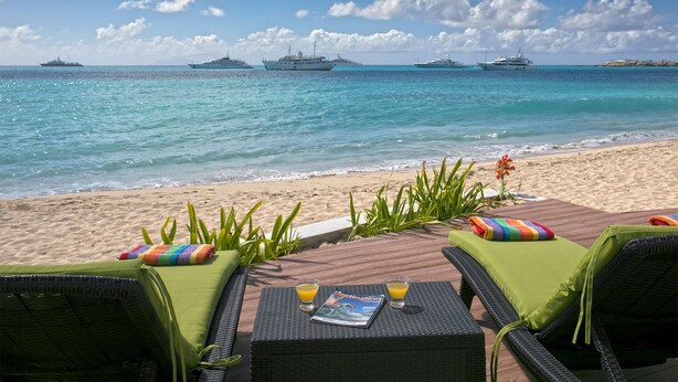 A beachside lounge with wicker furniture, a magazine, and glasses of orange juice.