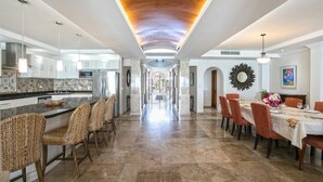 A spacious kitchen with a central island, modern appliances, and a dining area with a long table and chairs.