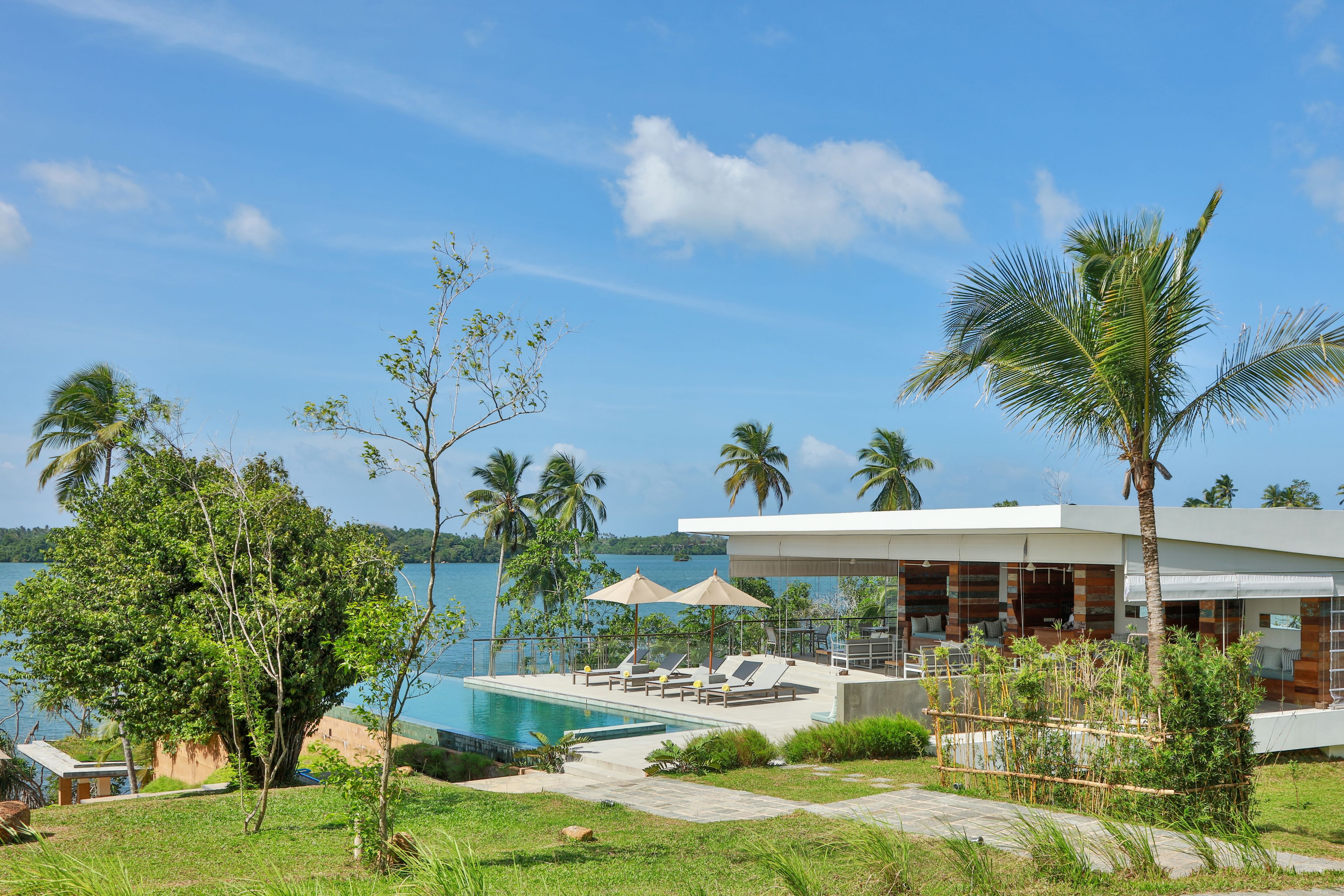 A modern resort with a pool, lounge chairs, and a view of the water.