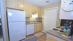 A kitchen with light wooden cabinets, a white refrigerator, a dishwasher, a sink, a stove, and a clock on the wall. - Club Ocean Villas II 88-Bayside 120th St, WIFI, W/D, AC (Ocean City)