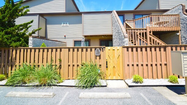 A row of modern, multi-story buildings with a wooden fence in front. - Club Ocean Villas II 88-Bayside 120th St, WIFI, W/D, AC (Ocean City)