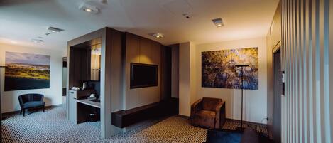 A modern living room with a large TV, a sofa, a chair, and a patterned carpet.