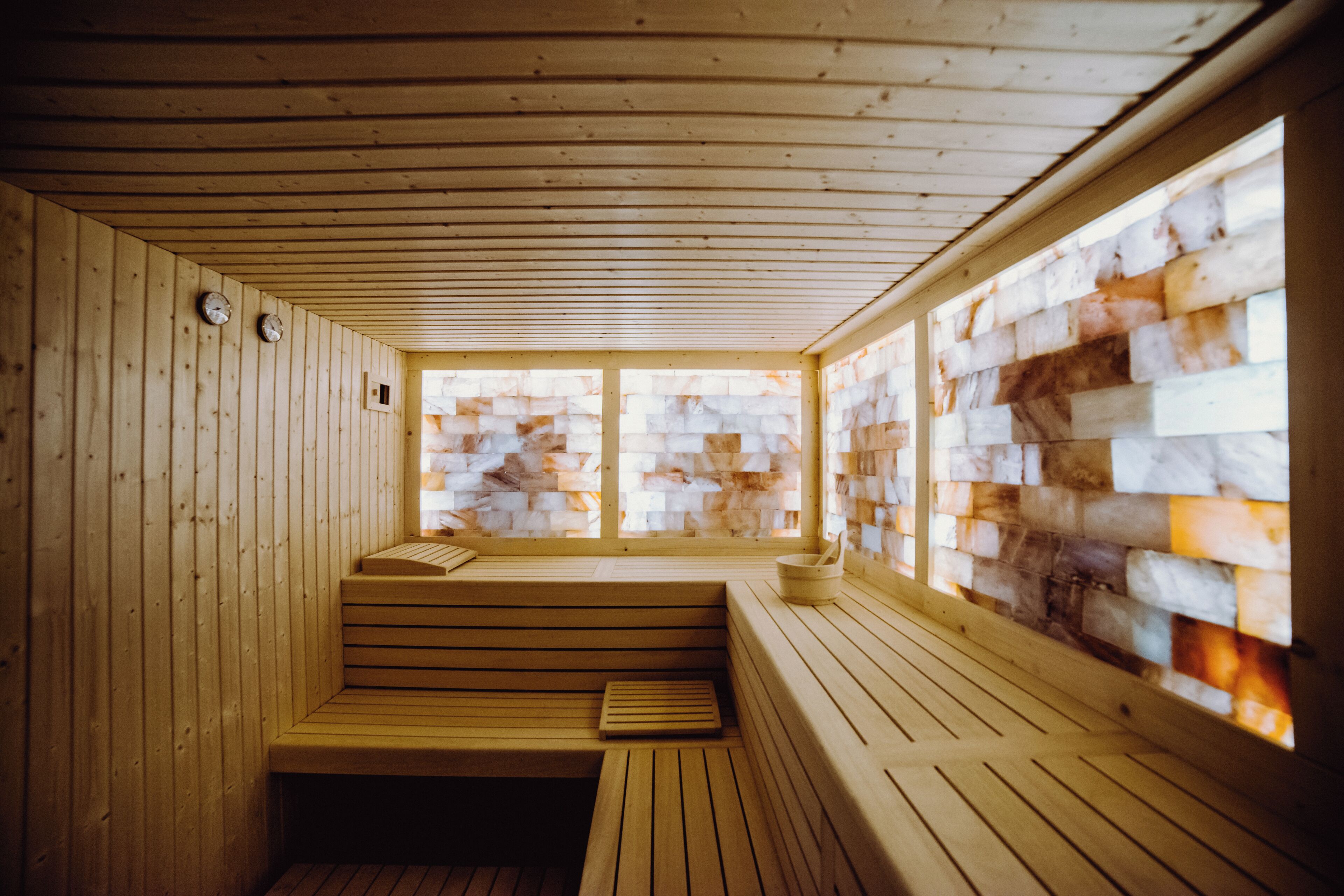 Una sauna de madera con bancos, un ventanal con mosaico y techo de madera.
