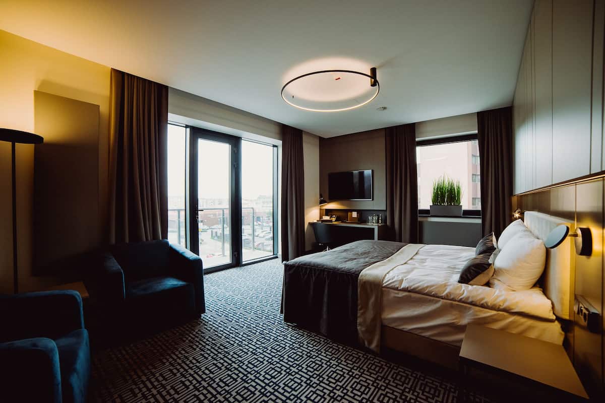 Habitación de hotel con una cama grande, un escritorio, un televisor y vistas a la ciudad.