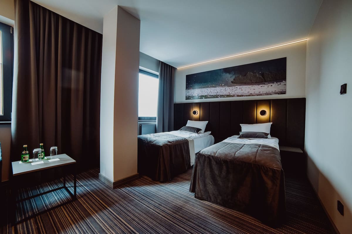 Habitación de hotel con dos camas, un escritorio y un ventanal grande.