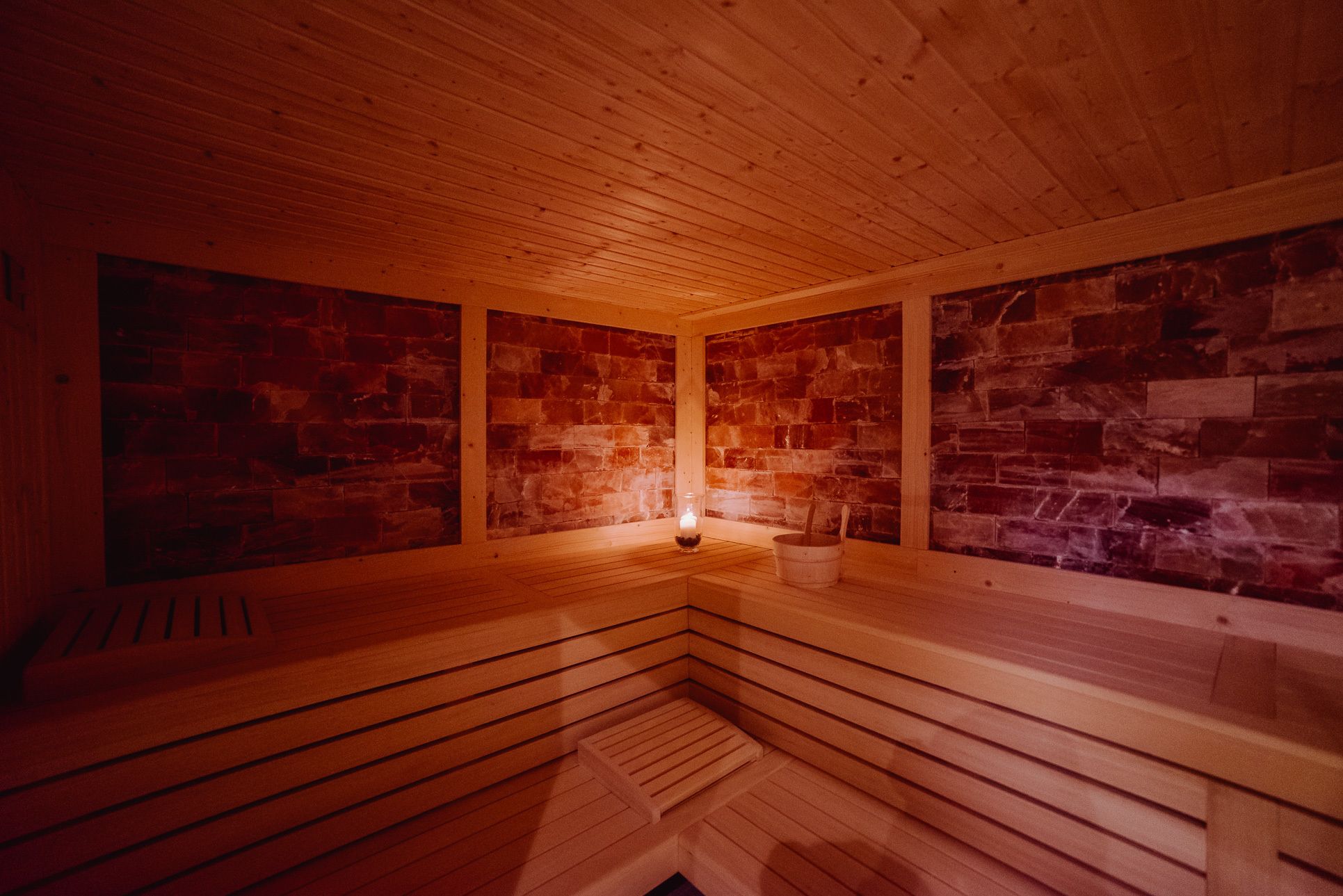 Un sauna avec des bancs en bois et des murs en pierre.