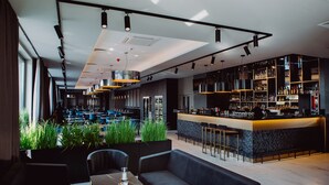 A modern bar area with a counter, seating, and a bar stocked with bottles.