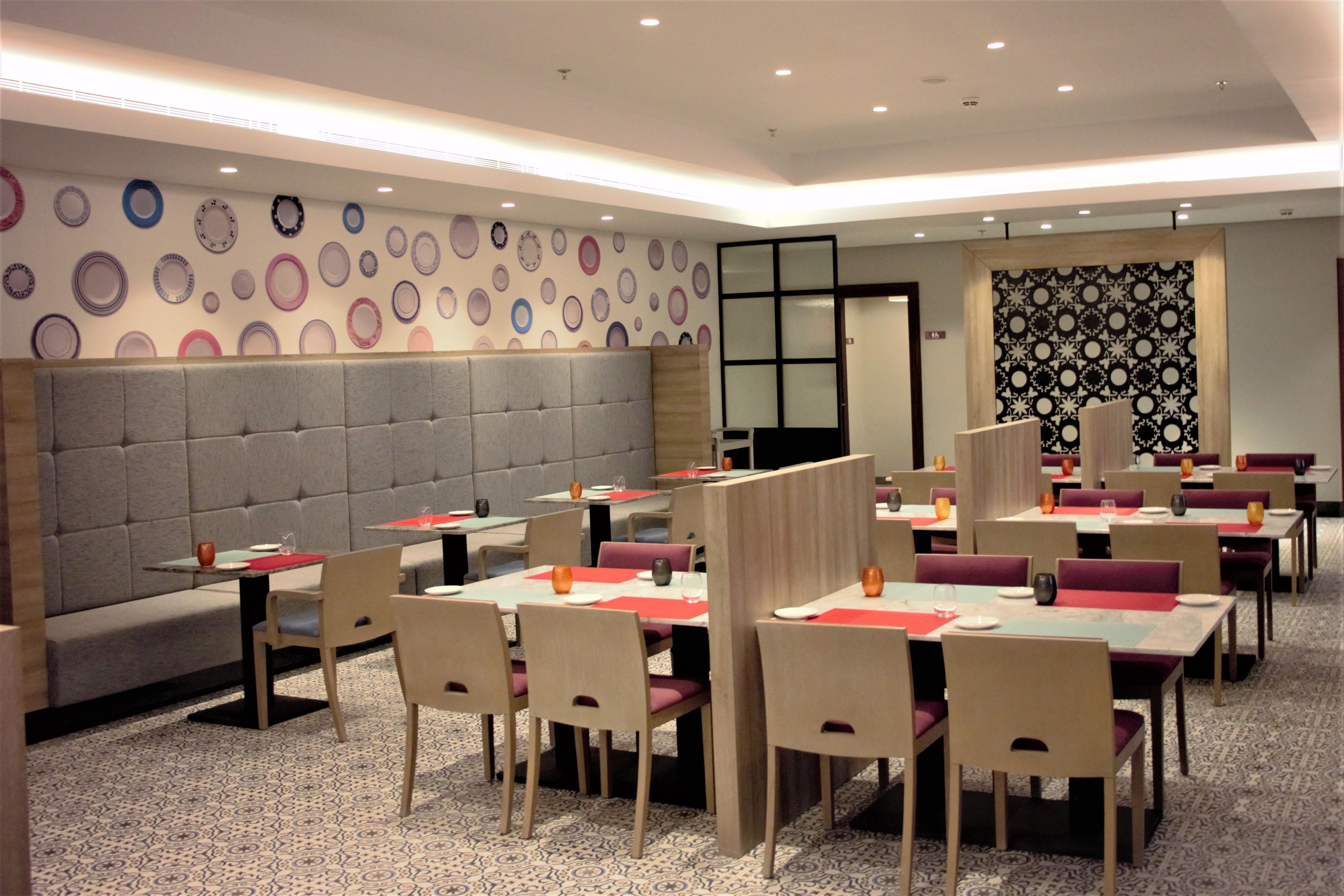 Um restaurante com várias mesas e cabines, parede estampada e tapete padronizado.