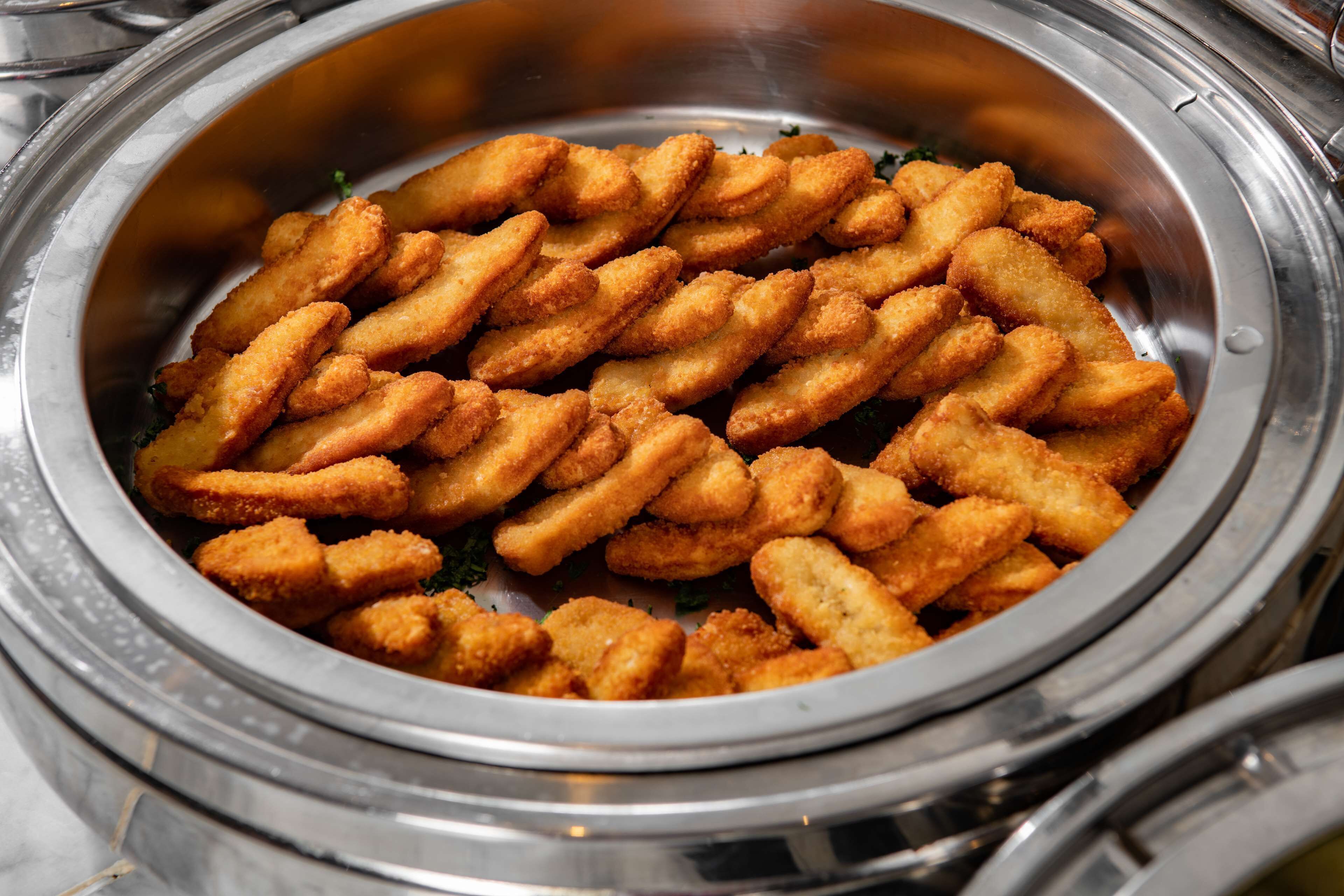 A buffet bowl filled with breaded and fried food items.