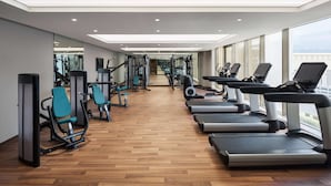 Un gimnasio con equipo de ejercicio, suelo de madera y ventanas amplias.