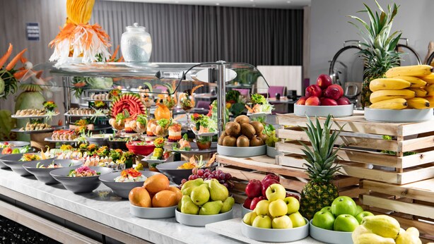 Un bufé con diversas frutas y verduras expuestas sobre una encimera de mármol.