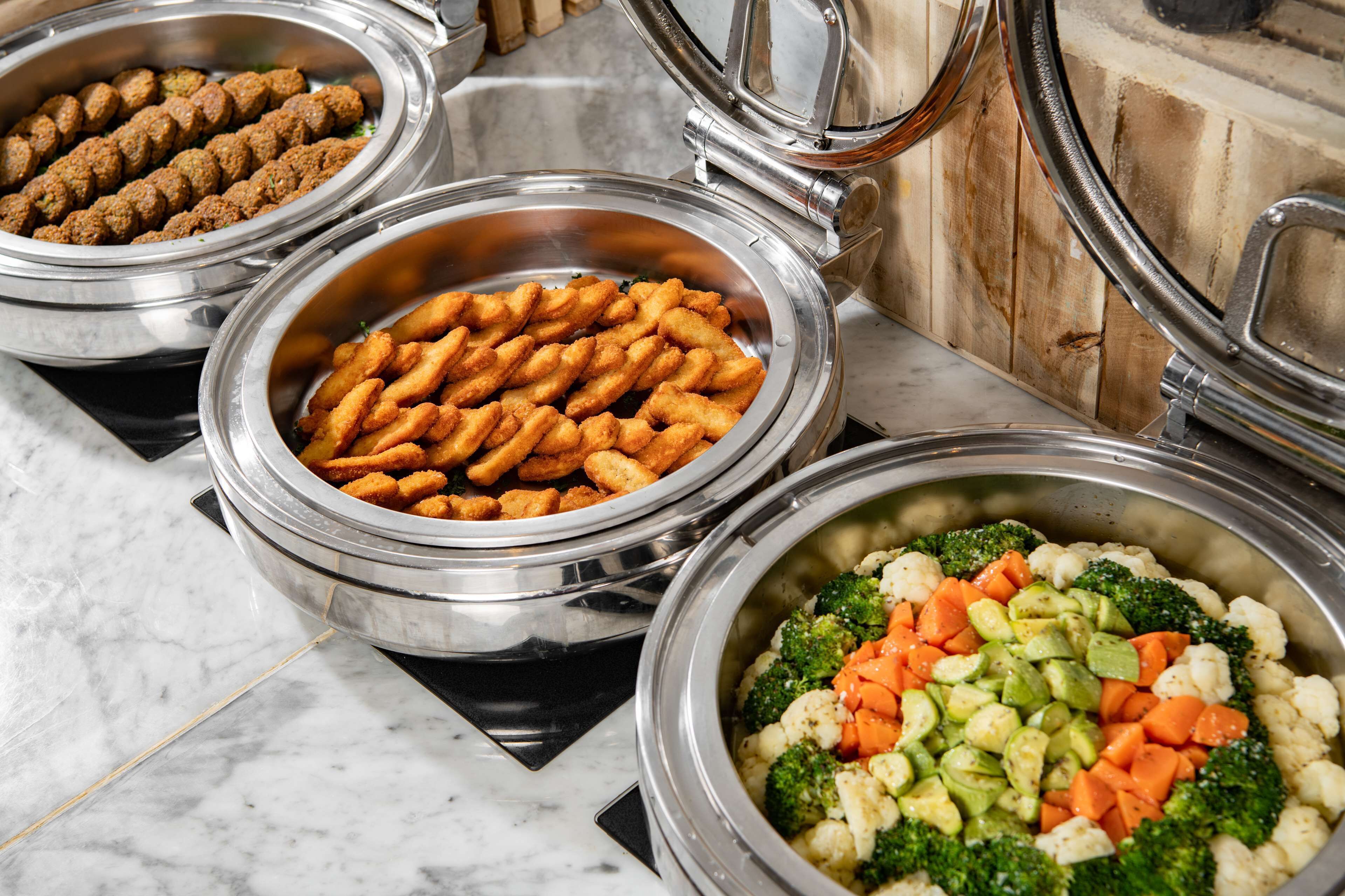 Three food service containers with various dishes, including meatballs, fried snacks, and mixed vegetables.