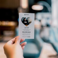A hand holding a hotel welcome card with a QR code and a heart-shaped photo.