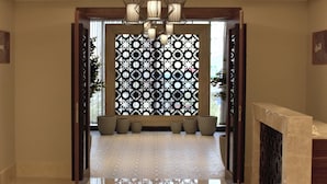 Un pasillo con un mamparo decorativo, suelo de baldosas y un banco de madera con cojines.
