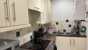 A compact kitchen with a microwave, stove, and sink. There are cabinets, a toaster, and a small refrigerator. - Chapel Apartments (Aberdeen)