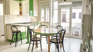 Een keuken met een ronde tafel en stoelen, een fornuis en een raam met jaloezieën.