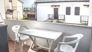 Een balkon met een witte tafel en twee witte plastic stoelen.