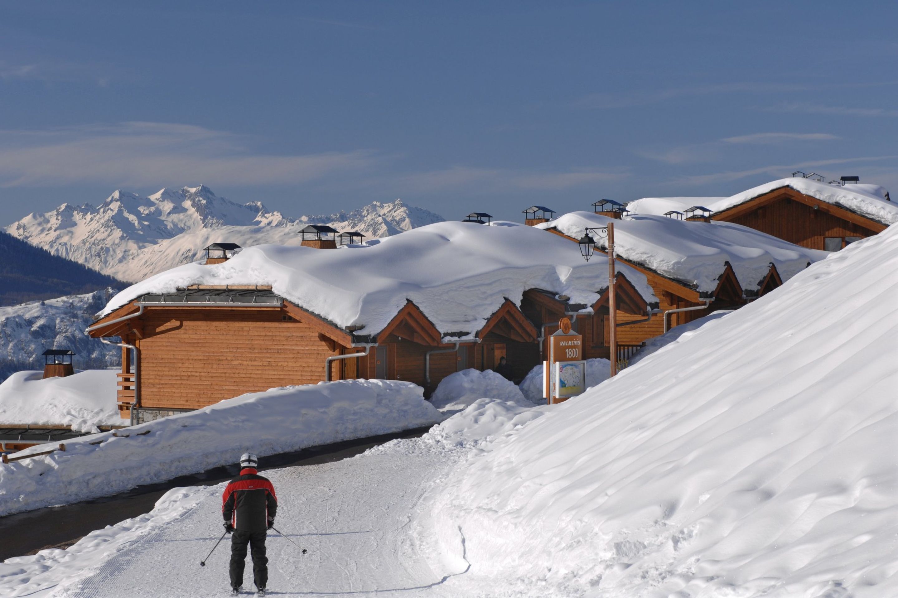 A ski resort with wooden chalets and a person skiing.