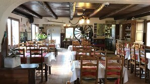 A rustic restaurant with wooden tables and chairs, a large wooden wheel, and a bar area. - Hotel Restaurant Le Ranch de Turini (La Bollene-Vesubie)