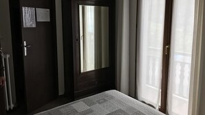 A bedroom with a large mirror, a door with a notice, and a window with curtains. - Hotel Restaurant Le Ranch de Turini (La Bollene-Vesubie)