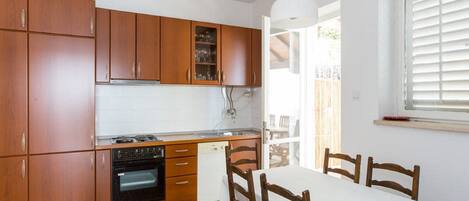 Una cocina compacta con armarios de madera, horno integrado y comedor con mesa y sillas.