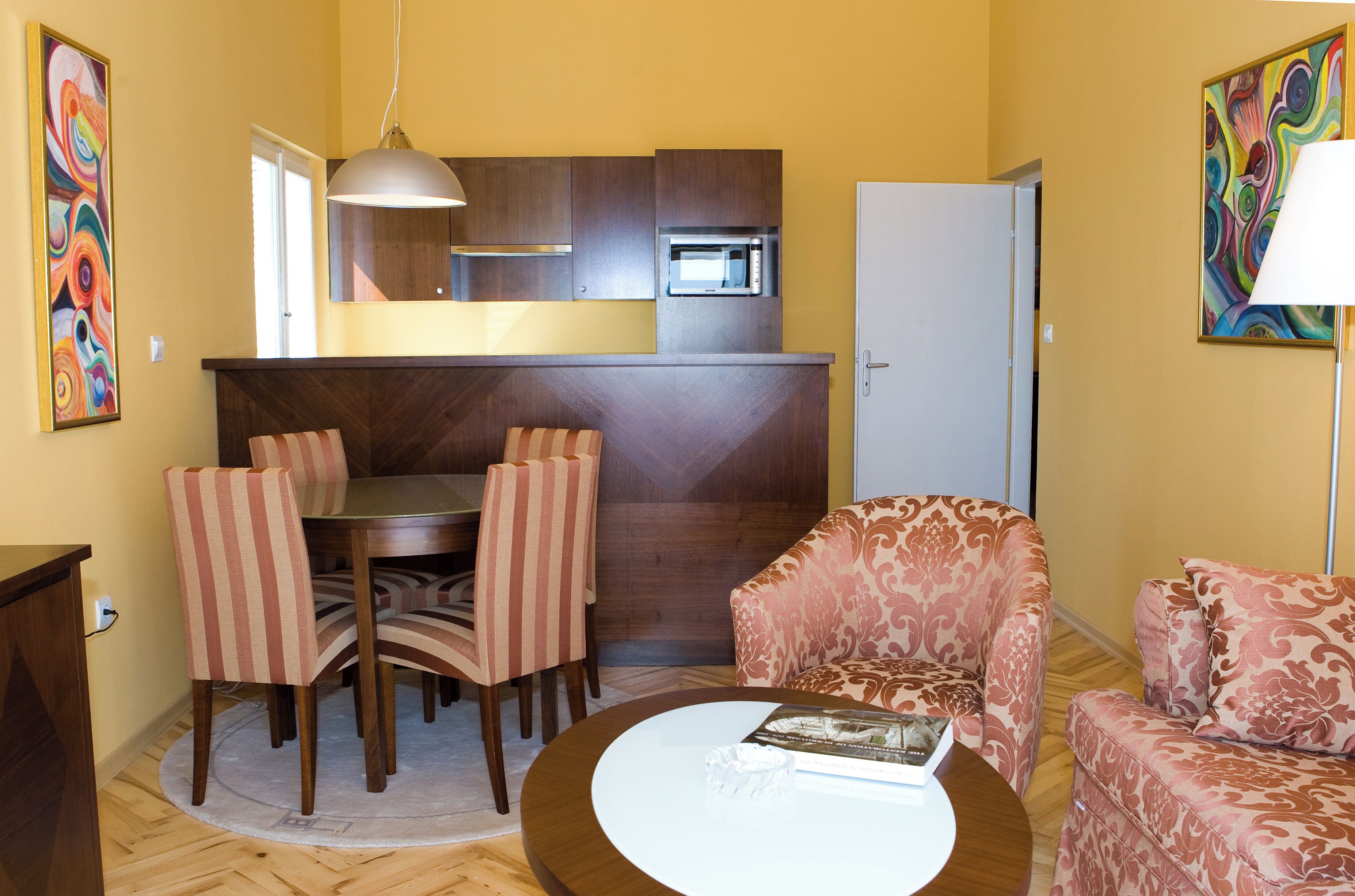 Un espacio habitable compacto con comedor, sofá, mesa de centro y zona de cocina con microondas.