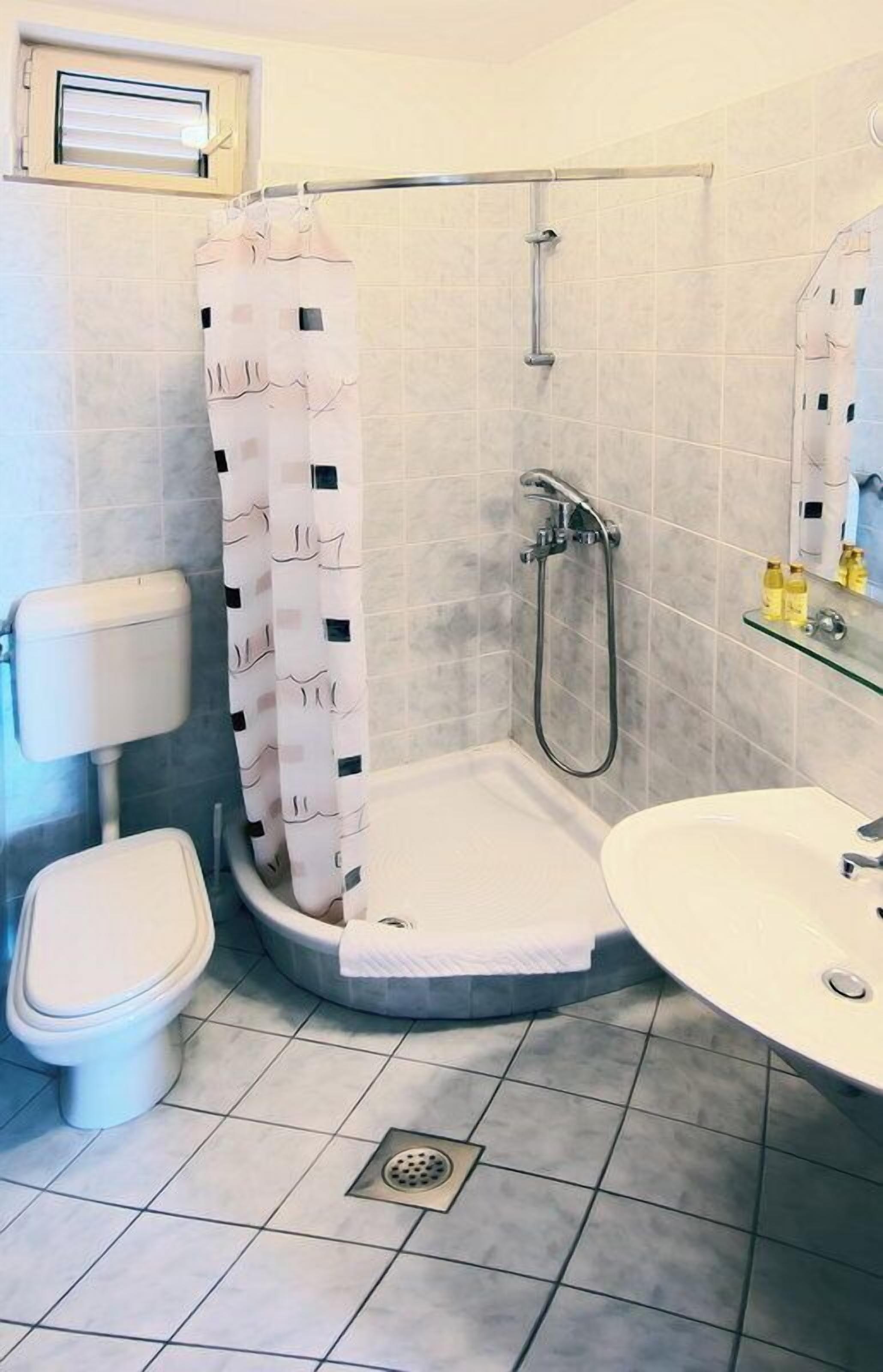 A bathroom with a shower, toilet, and sink.