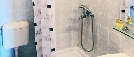 A bathroom with a shower, toilet, and sink.