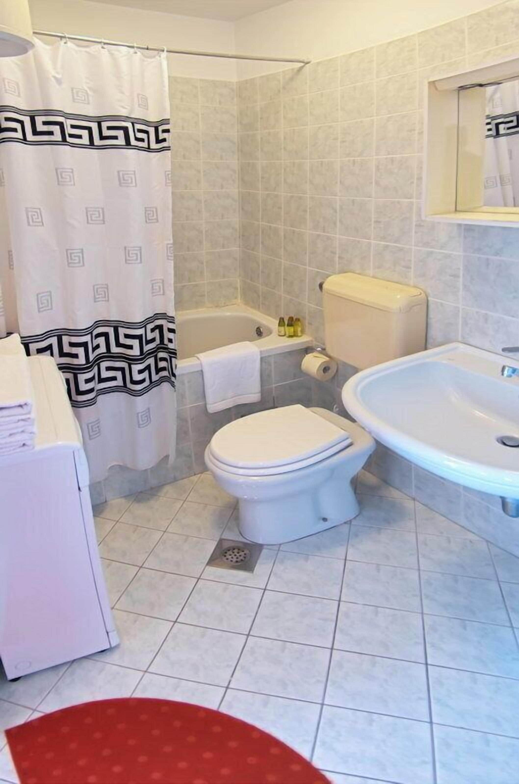 A bathroom with a toilet, bathtub, and sink.