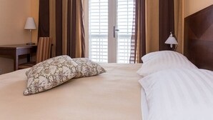A hotel room with a bed, a desk, a chair, and a lamp. - Sipa Apartments (Dubrovnik)