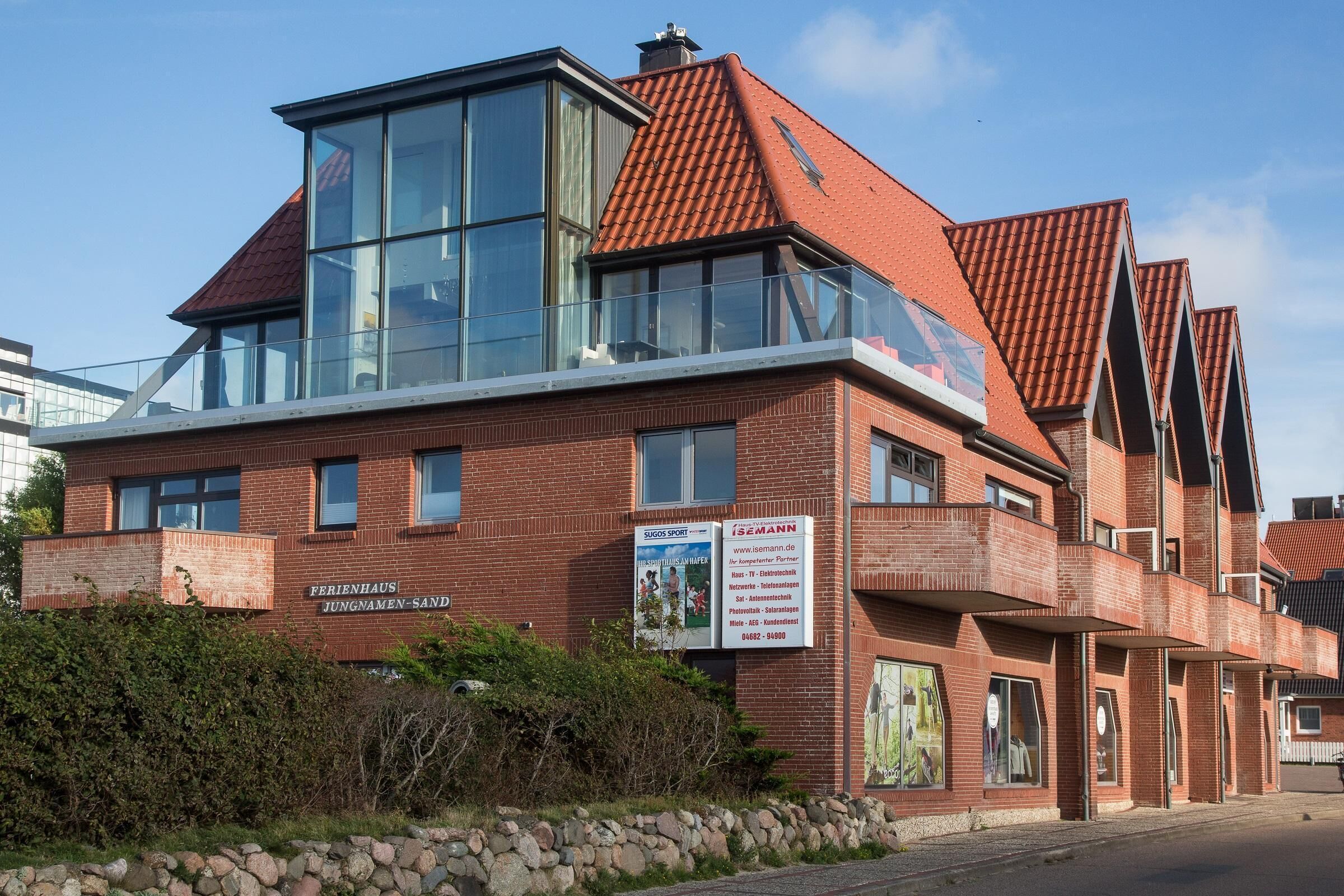 A multi-story building with a brick facade, large windows, and a sloped roof.
